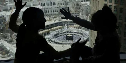 Doi copii se joacă la fereastra unui hotel de unde se poatevedea Mareea Moschee din Mecca. FOTO AP