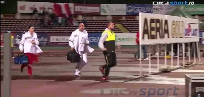 Medicii aleargă pe lângă ambulanță și se opresc în spatele porții, așteptând permisiunea arbitrului să intre pe teren