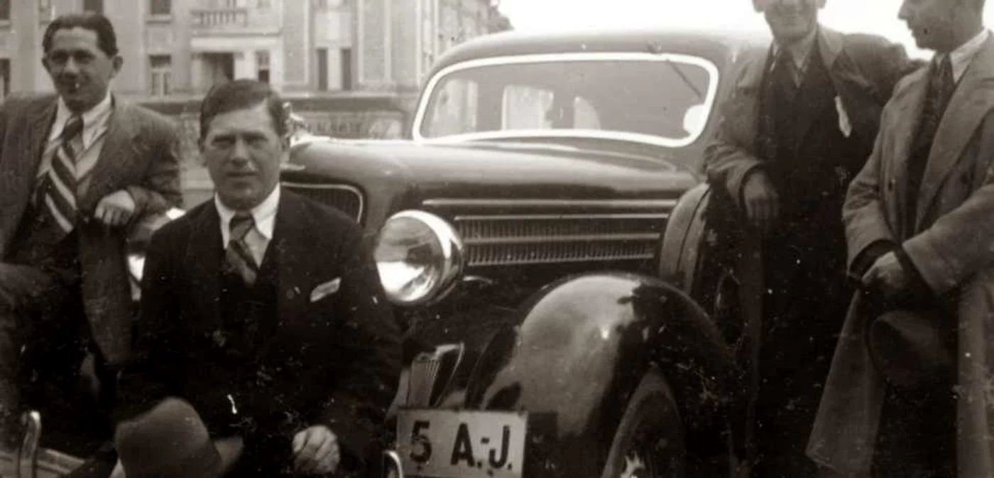 Bărbaţi îmbrăcaţi cu costume luxoase lângă o maşină ”la modă” în perioada din jurul anului 1930