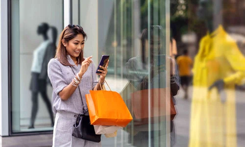asian woman using the smart mobile phone for check online shopping order is completed with clothes beside the glassess in store shop with happy action at department center 961515078 d885f0506450479c9efb38d9ddf1ed58 jpg