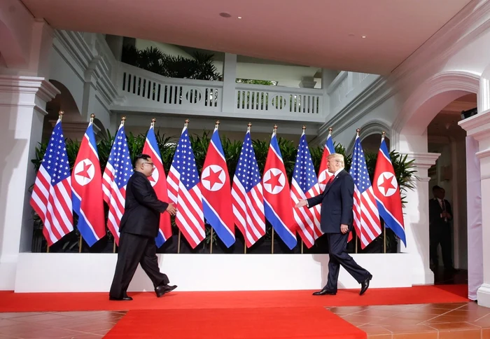 Kim Jong-un (stânga) şi Donald Trump, spre prima strângere de mână între un lider al regimului comunist de la Phenian şi un preşedinte american FOTO EPA