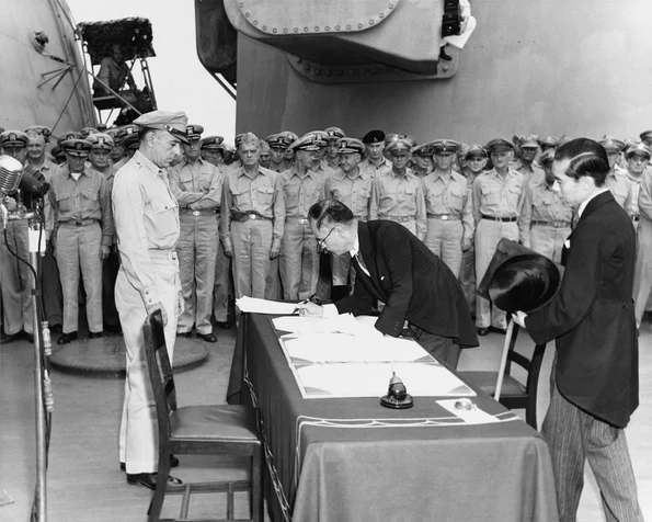 Ministrul de Externe al Japoniei, Mamoru Shigemitsu, semnează capitularea Japoniei, la bordul navei USS Missouri, în fața generalului american Richard K. Sutherland, la 2 septembrie 1945 (© Naval Historical Center Photo # SC 213700)
