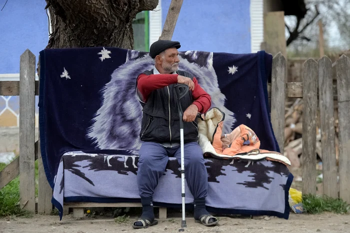 Un bătrân stă liniștit, pe o bancă, de parcă nimic nu s-ar întâmpla în jurul lui