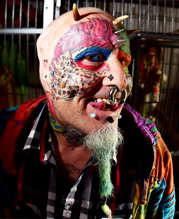Are 110 tatuaje, 50 de piercing-uri și o limbă despicată