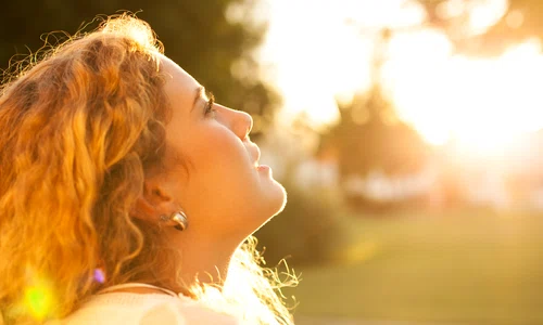 young woman with curly hair enjoying sunny day jpg