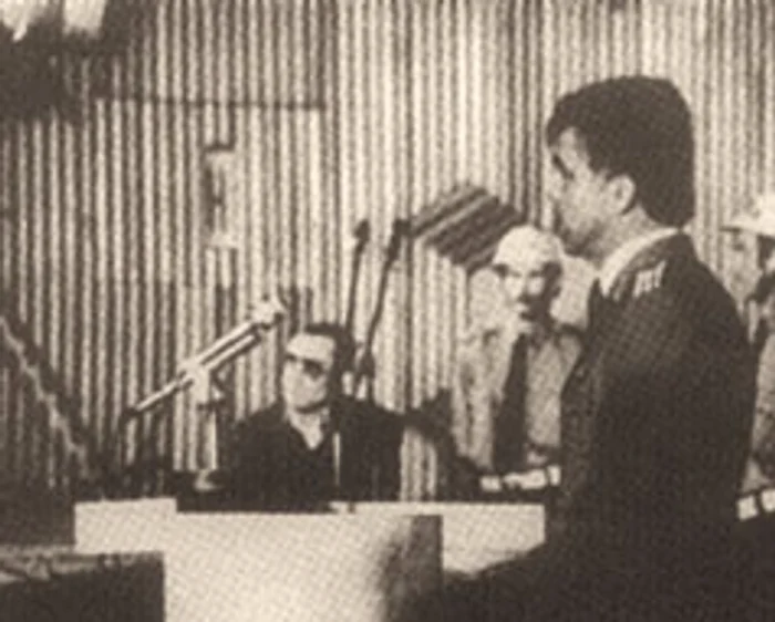 Locotenent-colonel Aurel Dragomir, interogat la procesul lui Nicu Ceauşescu (cu ochelari, în plan îndepărtat)