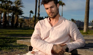 young hispanic male wearing pink shirt posing beach near palm trees jpg