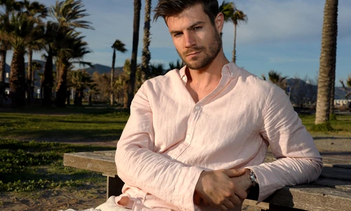 young hispanic male wearing pink shirt posing beach near palm trees jpg