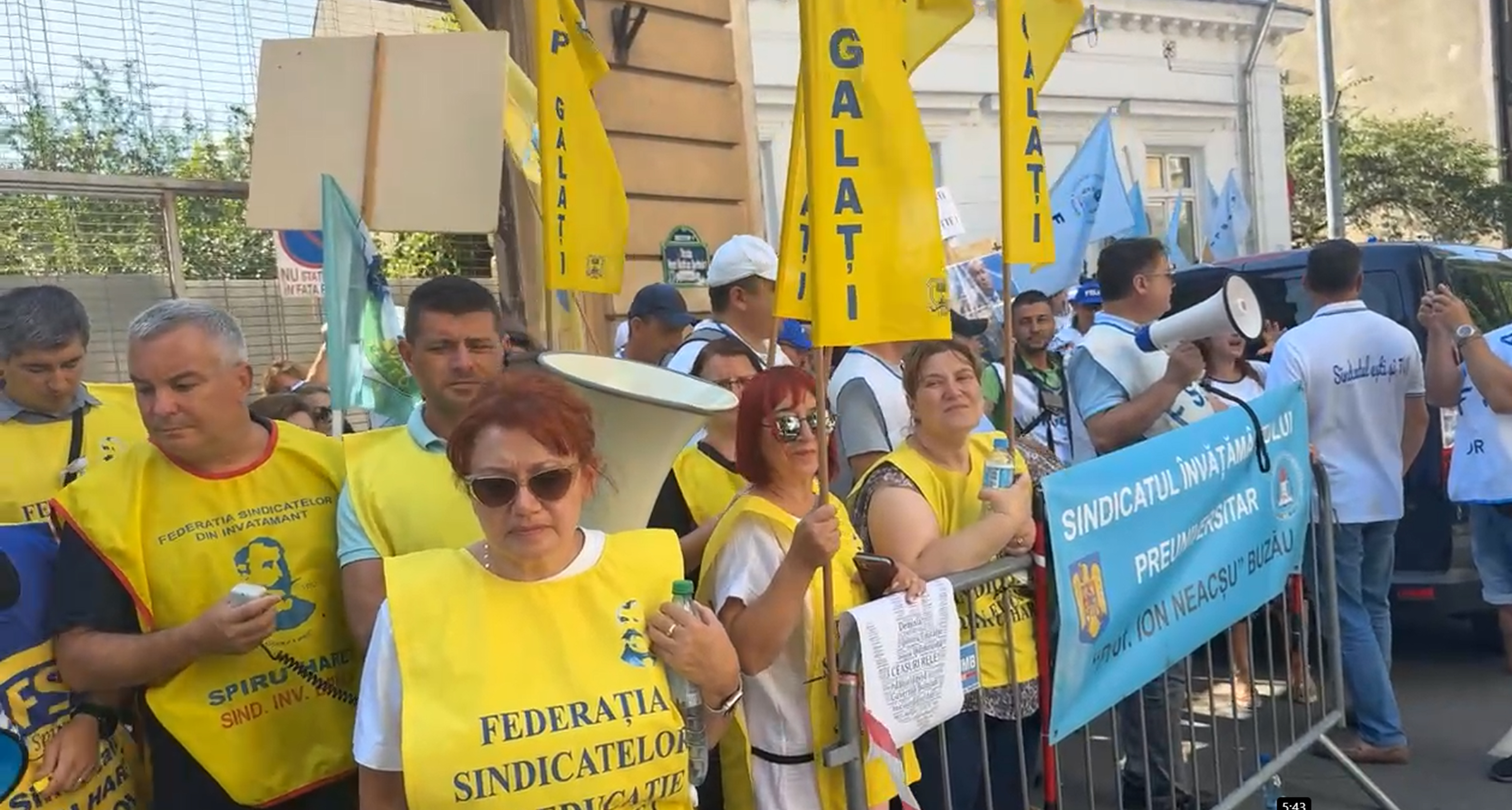 Sindicaliști din educație îmbrăcați în galben cu pancarte la protest