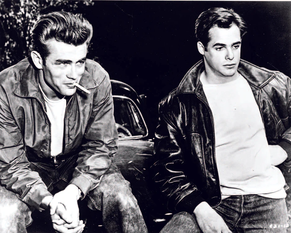 Actorii James Dean și Correy Allen (de la stânga la dreapta) într-o scenă din filmul „Rebel fără cauză”. James Dean a popularizat imaginea „băiatului-rău”, din uniforma căruia geaca de piele era nelipsită.