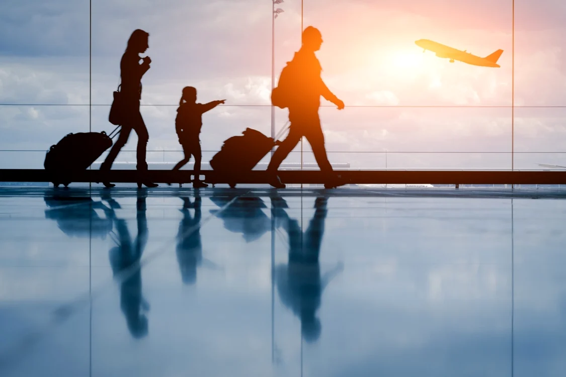 Familie cu un copil și două trolere pe un aeroport
