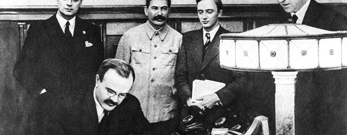 Molotov semnează Pactul germano-sovietic de neagresiune. În spatele lui se află Ribbentrop şi Stalin.