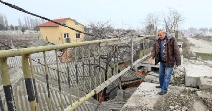 Mihai Drăceanu arată de unde s-au desprins bucăţile de beton care i-au căzut în curte  