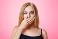 plesant looking light haired female dressed casually covers mouth with hand tries keep silent tell secret isolated pink wall people beauty body language concept jpg