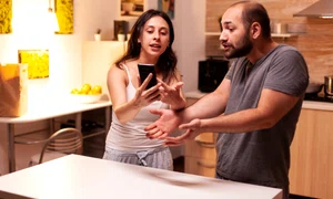 woman pointing phone while reading messages infidel husband while having disagreement heated angry frustrated offended irritated accusing her man cheating jpg
