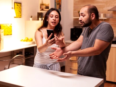 woman pointing phone while reading messages infidel husband while having disagreement heated angry frustrated offended irritated accusing her man cheating jpg