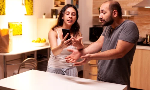 woman pointing phone while reading messages infidel husband while having disagreement heated angry frustrated offended irritated accusing her man cheating jpg