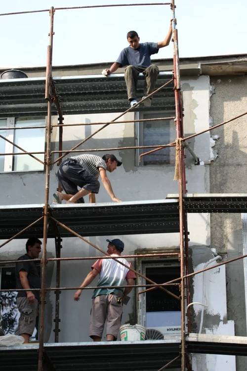 
    Muncitorii urcă pe schelă neechipaţi corespunzător  