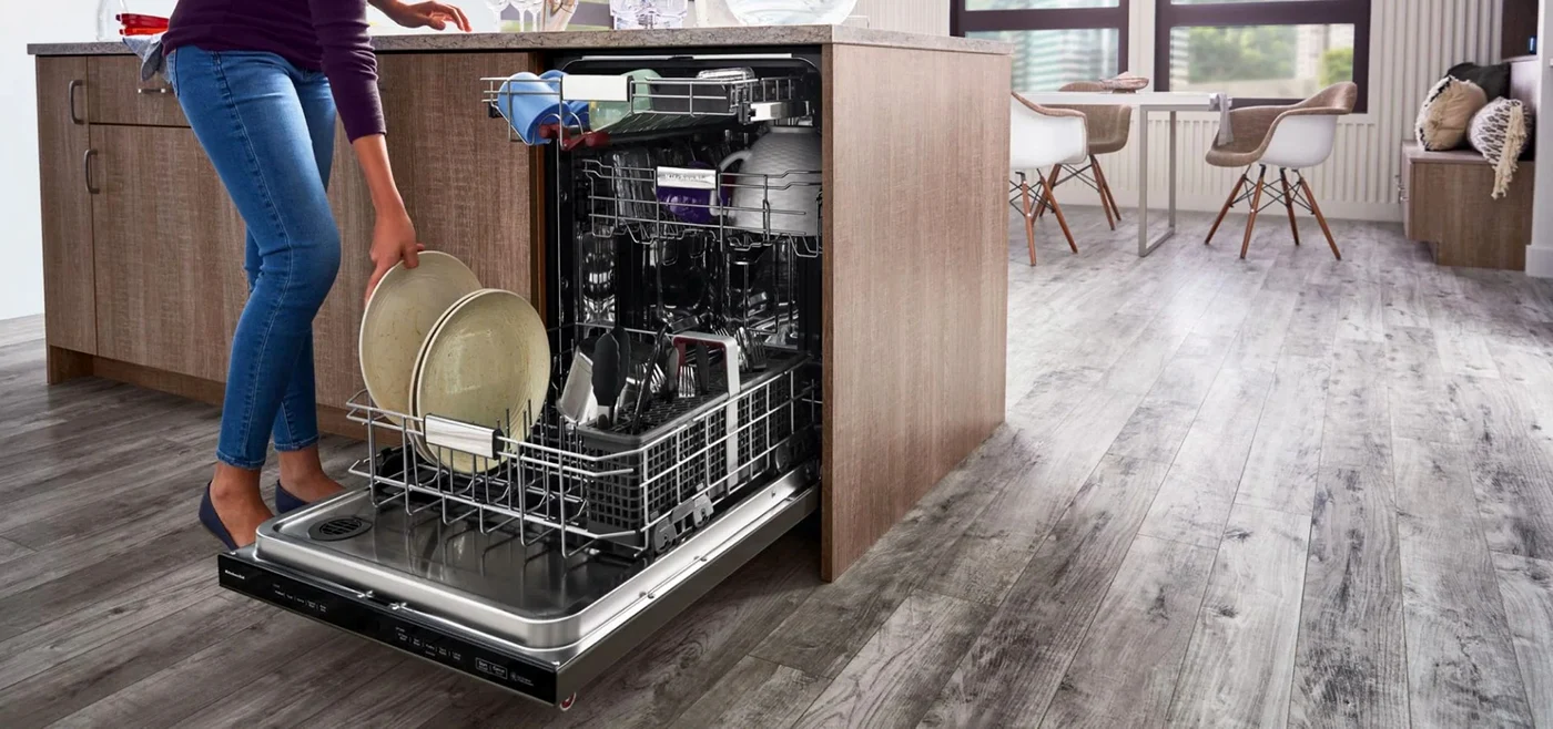 Femeie pune vesela în mașina de spălat vase încorporabilă Sursă KitchenAid jpg