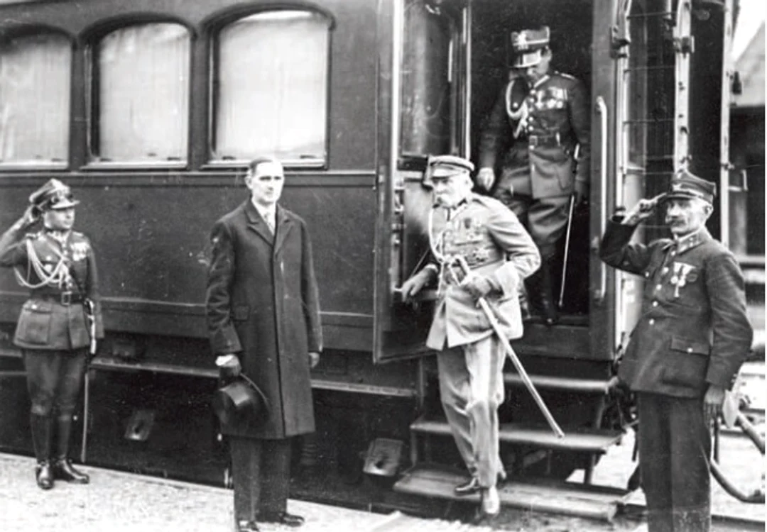 Piłsudski,  întâmpinat în Gara de Nord din București,  la întoarcerea din Egipt și în drum spre Polonia,  în aprilie 1932. În ușa vagonului este aghiotantul Mareșalului,  căpitanul Mieczysław Lepecki. În stânga,  pe peron: dr. Lucjan Skupiewski și căpitanul Jan Derecki,  atașatul militar adjunct în România