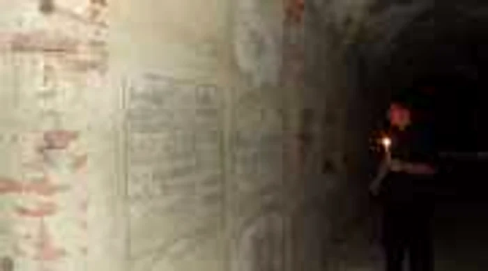 Preotul Teodor Lazăr cu o lumânare în mână, în cripta de sub biserica unde slujeşte (foto: cluj.travel)