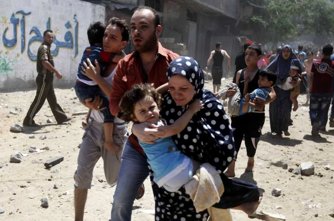 O familie de palestinieni fuge după ce zona în care locuieşte a fost lovită de o rachetă israeliană. FOTO Reuters