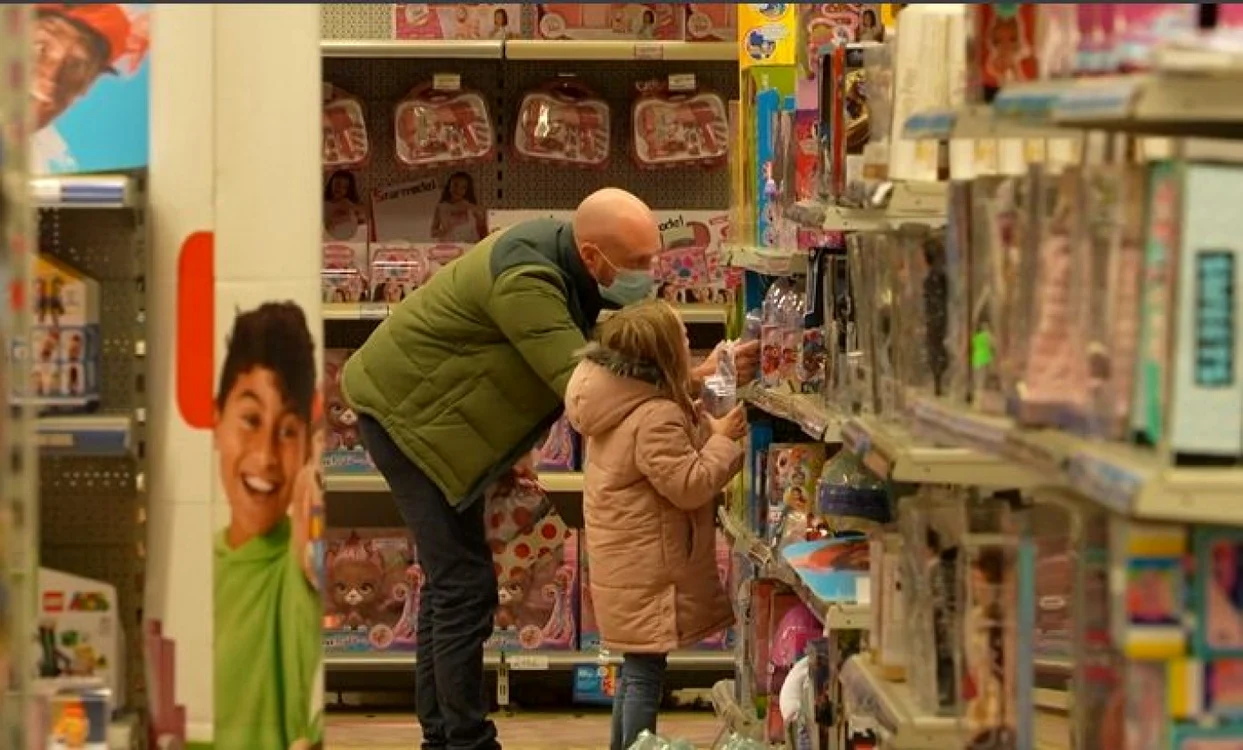 Un bărbat îi arată fiicei sale mai multe jucării într-un magazin