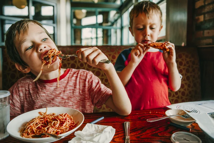 Copii mâncând spaghete și pui în restaurant