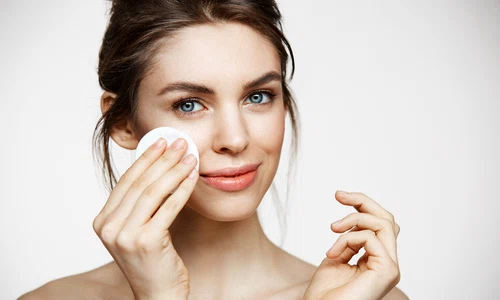 cute beautiful natural brunette girl cleaning face with cotton sponge smiling looking camera white background cosmetology spa jpg