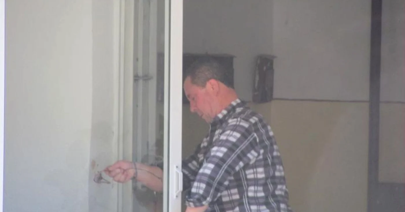 Unul dintre vecini montează uşa distrusă