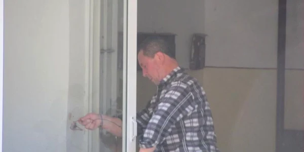 Unul dintre vecini montează uşa distrusă