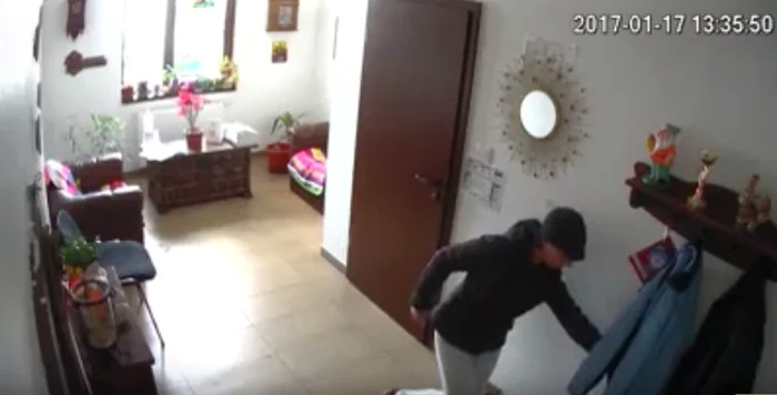 Femeia, în timp ce sustrage portofelul dintr-o haină lăsată pe hol de un alt client al cabinetului