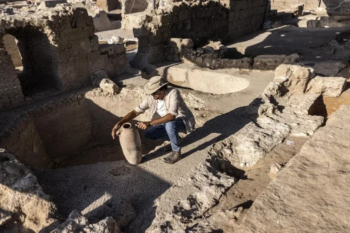 FOTO: AP / Un arheolog inspectează un vas de lut în crama veche de 1500 de ani descoperită în Yavne, Israel