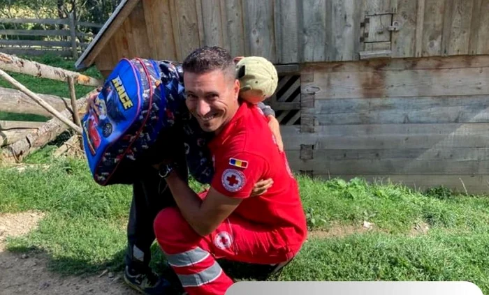 Copilul fericit îl îmbrățișează pe voluntarul care i-a dat ghiozdanul FOTO Crucea Roșie Alba