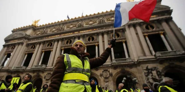 Un bărbat ridică steagul naţional în faţa Operei în timpul unei demonstraţii a Vestelor Galbene la Paris Franţa FOTO EPA-EFE / Ian Langsdon