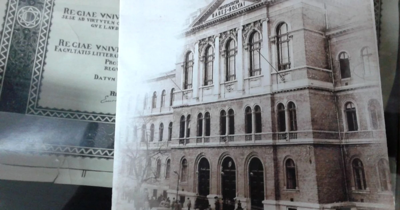 Imaginea clădirii centrale a UBB pe o broşură cu istoricul instituţiei. În spate, diploma prin care Regina Maria a devenit DHC a universităţii (imagine din muzuel de Istorie al UBB)  FOTO: Florina Pop