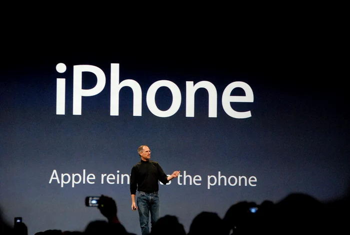 Steve Jobs, în 2007, prezentând publicului în stilu-i caracteristic primul telefon IPhone din istorieFoto: en.wikipedia.org