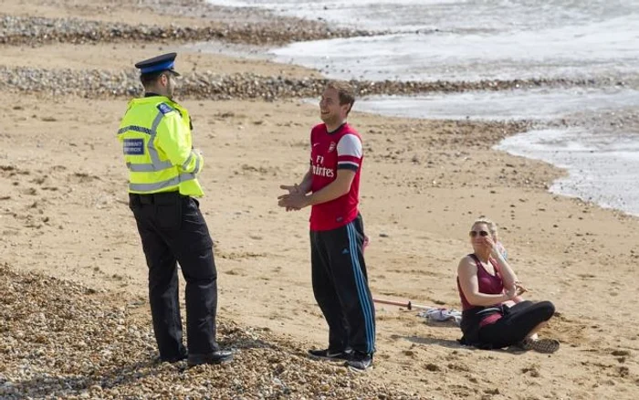 Un ofiţer de poliţie britanic cerându-le unor oameni să plece de pe plajă în timpul perioadei de autoizolare naţională                                                                                                      FOTO: David McHugh/ Daily Mail