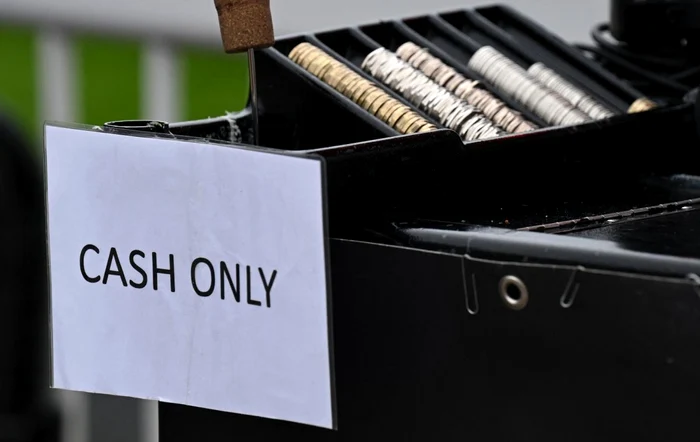 Afiș pe geamul unei bănci cu mesajul Cash Only (doar numerar)