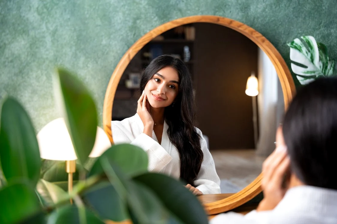Femeie care se admiră în oglindă - frumusețe naturală Foto Herbalife