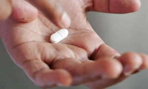 white pill being taken from palm of hand webp