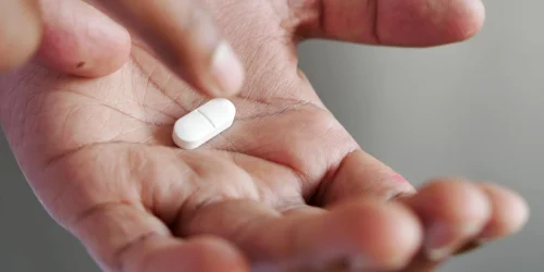 white pill being taken from palm of hand webp