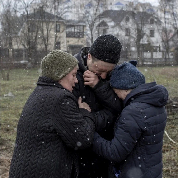 NBC NEWS: Familie de ucraineni plângând după ruda dispărută lângă groapa comună de la Bucia, în Ucraina.