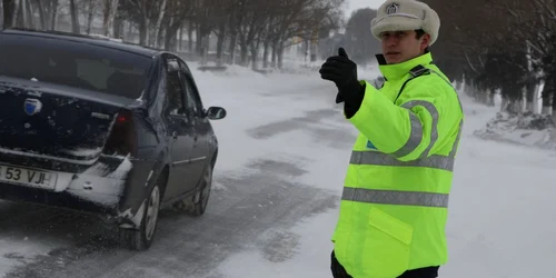 Politist dirijeaza traficul pe ninsoare