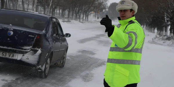 Politist dirijeaza traficul pe ninsoare