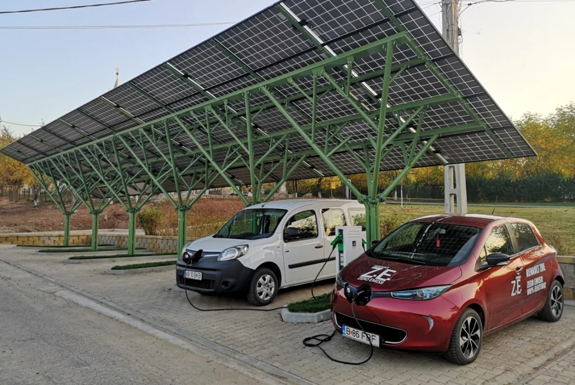 Două mașini electrice, una albă și una roție, puse la încărcat