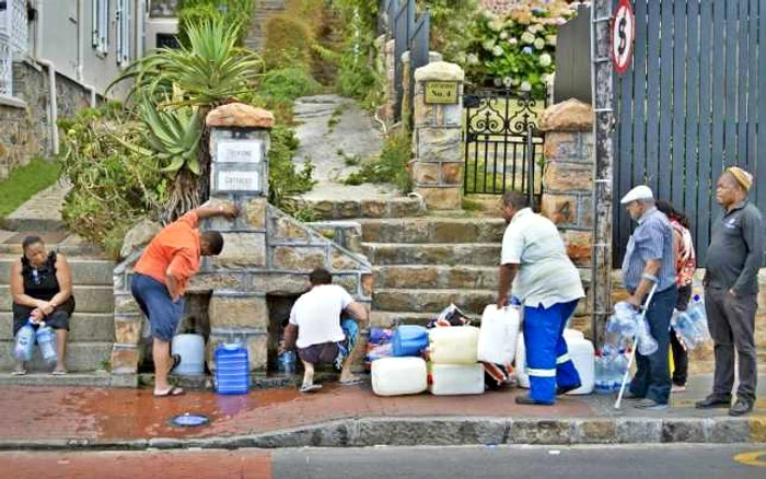 Locuitori ai oraşului Cape Town făcând rost de apă FOTO AFP