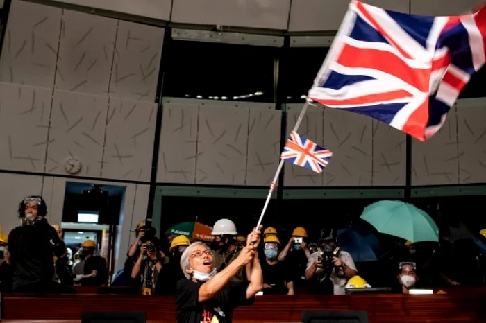 Un protestatar flutură steagul colonial britanic în clădirea Parlamentului din Hong Kong FOTO AFP