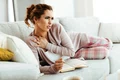 young woman having neckache while relaxing sofa reading book home jpg