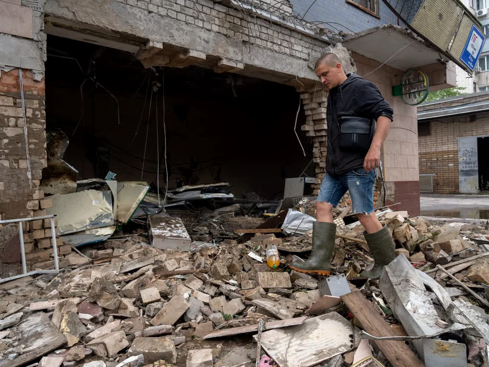 Un rezident local curăță resturile unui magazin distrus în Herson. Foto: Getty Images